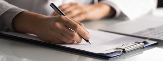 Image of a hand writing on clipboard.