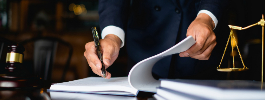 Image of a lawyer writing at a desk with the Scales of Justice.