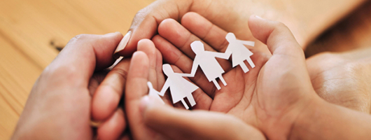 Image of hands holding a cut out of paper representing a family.